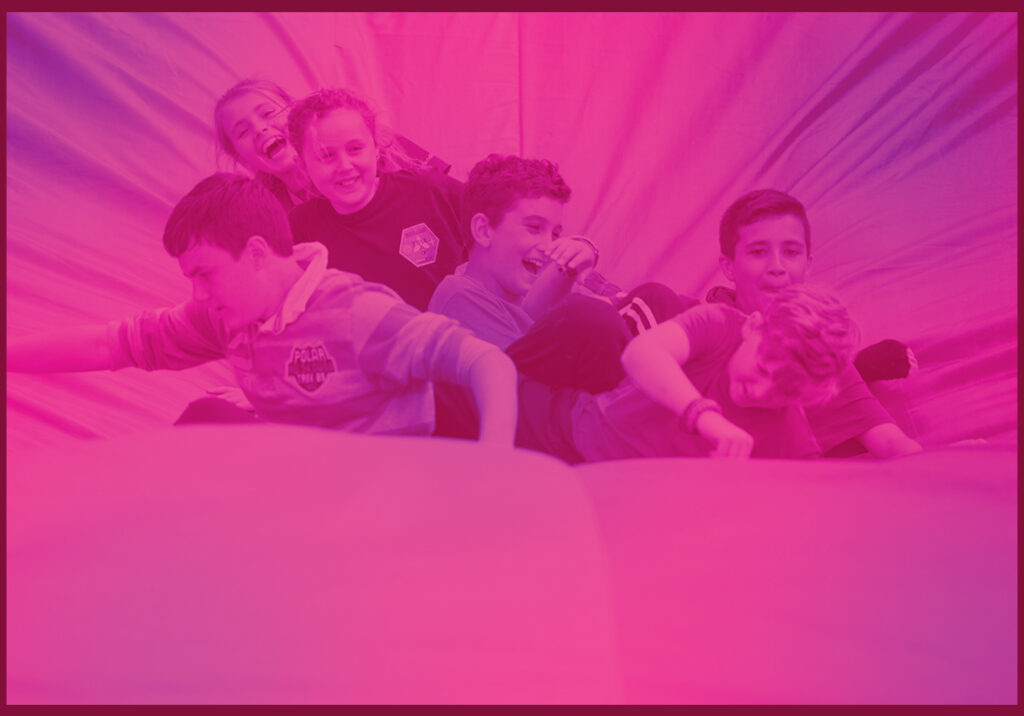 A vibrant pink image showing young people at the Jamboree enjoying inflatables.